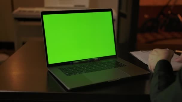 Un homme se prépare à prendre des notes d'apprentissage en ligne sur un ordinateur portable avec un écran vert - Séquence, vidéo
