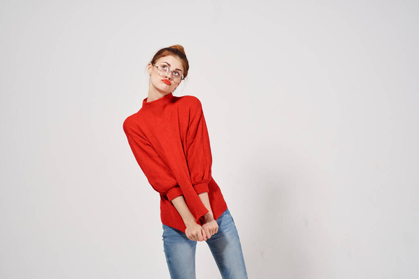 woman in a red sweater and jeans on a light background hairstyle glasses model emotion - 写真・画像