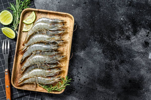 Whole fresh raw langoustine prawns, shrimps on a wooden tray. Black background. Top view. Copy space. - Foto, Bild