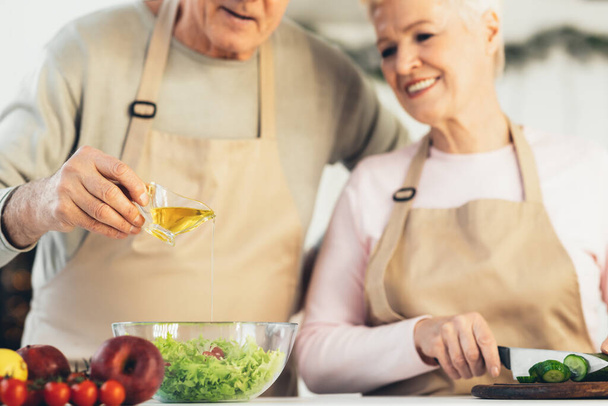 Tuntematon vanhempi pari ruoanlaitto salaatti ruoanlaitto illallinen keittiössä, rajattu - Valokuva, kuva