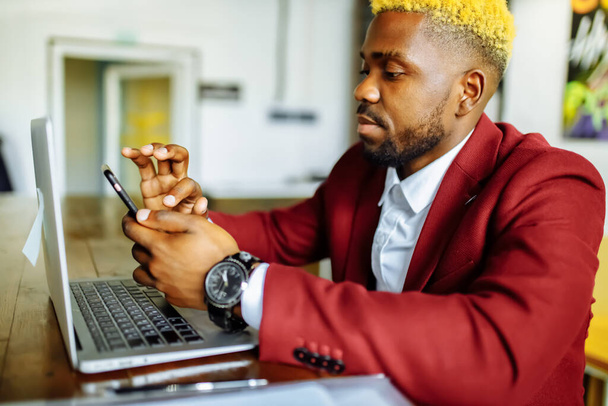 african american person sitting at office typing message note on phone near laptop - Foto, Bild