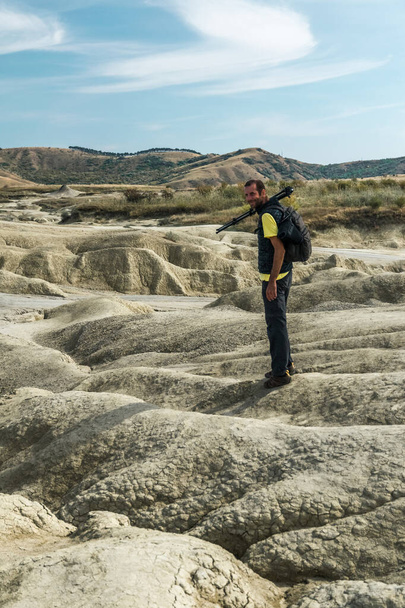 Турист з рюкзаком досліджуючи грязьовий вулкан у Румунії триногою. - Фото, зображення