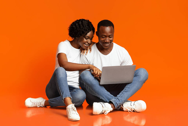 Χαλαρωμένο ζευγάρι Αφροαμερικανών που χρησιμοποιούν φορητό υπολογιστή μαζί - Φωτογραφία, εικόνα