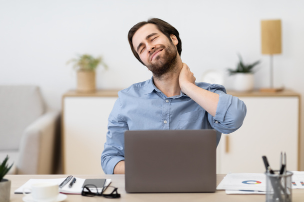 Unavený podnikatel masáže Bolavý krk sedí na notebooku v kanceláři - Fotografie, Obrázek