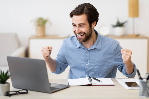 Guy no laptop balançando punhos celebrando o sucesso no escritório moderno - Foto, Imagem