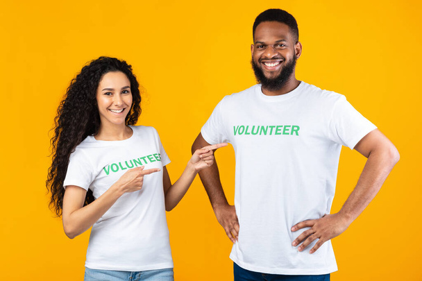 Woman Volunteer Pointing Fingers At Male Colleague Over Yellow Background - Foto, immagini