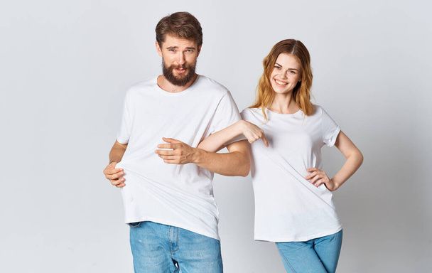 hombre emocional en una camiseta y una mujer en pantalones vaqueros sobre un fondo claro ropa estilo de moda - Foto, imagen