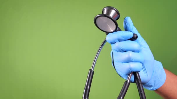 mano del médico en guantes protectores sosteniendo estetoscopio  - Metraje, vídeo