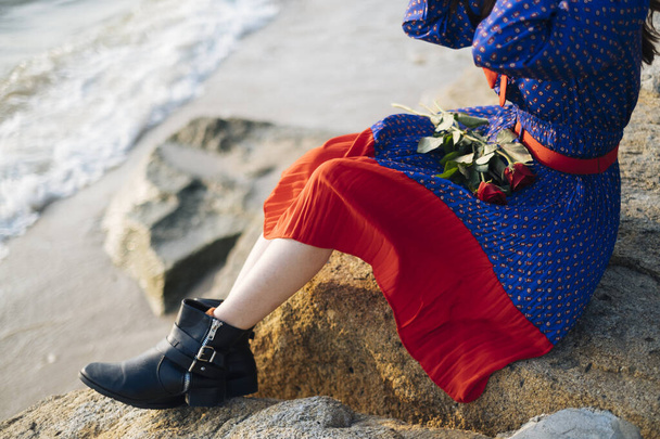 Kırpılmış gül resmi ve sahildeki kayada oturan kadın cesedi.. - Fotoğraf, Görsel