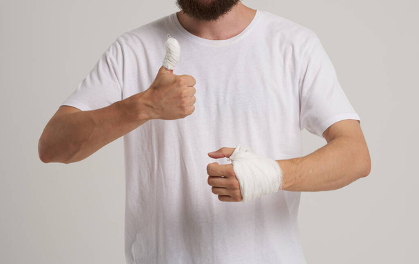 uomo che indossa bianco t-shirt paziente bendato problemi di salute della mano pronto soccorso - Foto, immagini