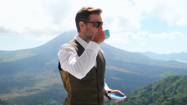 Liikemies juo kahvia. backgroud järvi ja vuoret - Materiaali, video