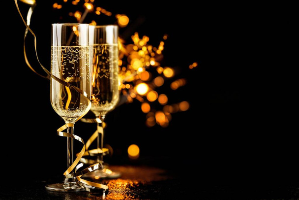 champagne glasses with golden ribbon and  sparkles on black background - new year celebration - Photo, Image