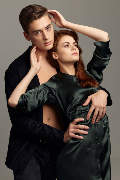 A man in an unbuttoned black shirt and a sexy woman in a dress cropped view - Photo, Image