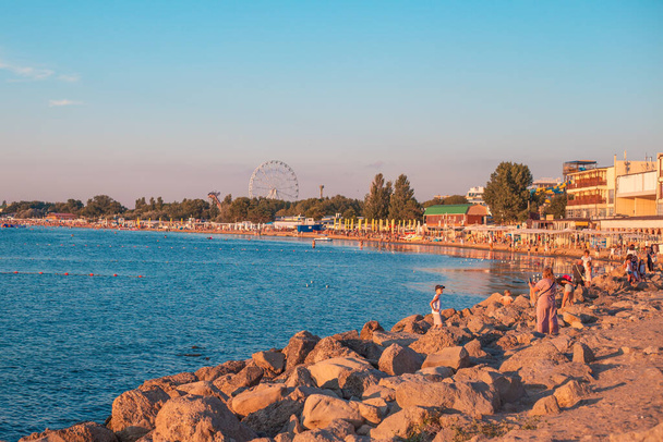 Anapa, Russia - 08.12.20: Black Sea Coast. Vacationers are photographed against the background of the sea on the coastline at sunset. - Foto, Imagem