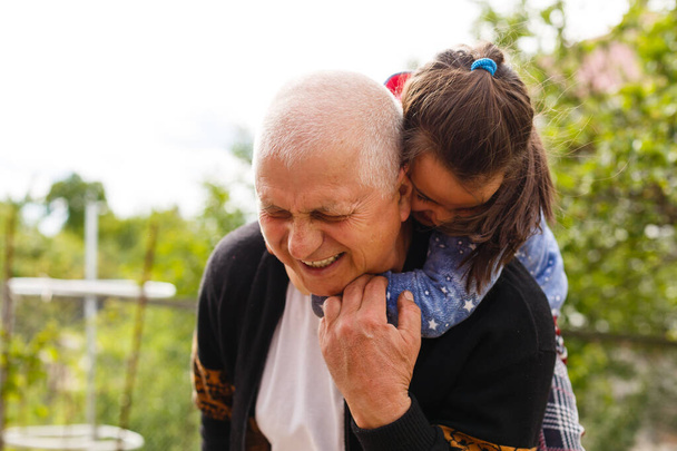 Funny lifestyle portrait of grandchild embracing grandfather - Photo, Image