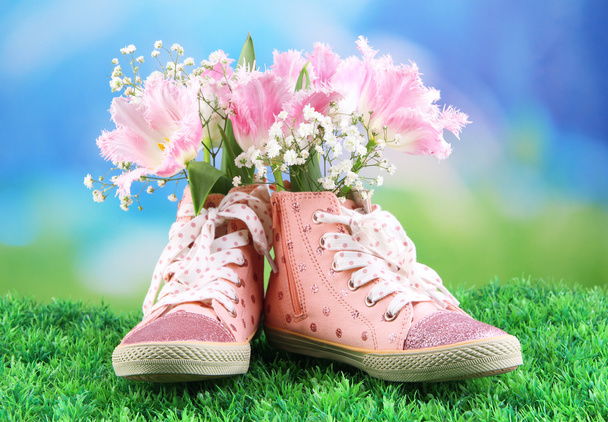 Beautiful gumshoes with flowers inside on green grass, on bright background - Foto, afbeelding