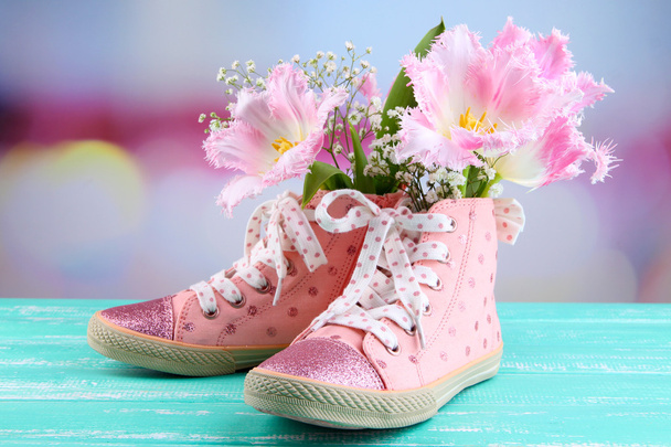 Beautiful gumshoes with flowers inside on wooden table, on bright background - Photo, Image