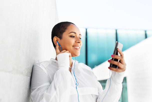 african american woman with earphones and phone - Photo, image