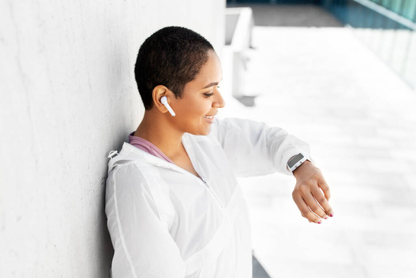 african woman with earphones and smart watch - Photo, image