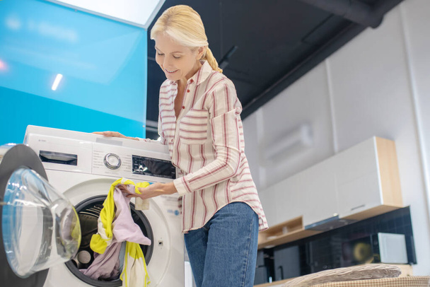 Blonde femme au foyer prenant des vêtements de la machine à laver - Photo, image