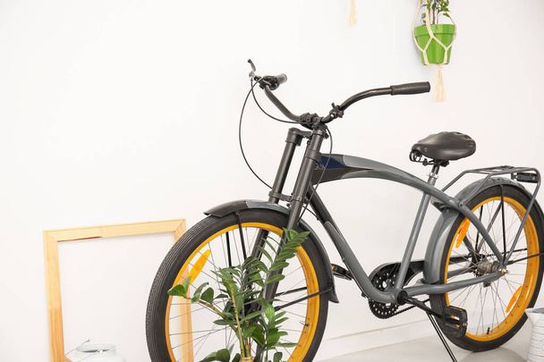 Bicicleta moderna con plantas de interior cerca de pared blanca - Foto, Imagen