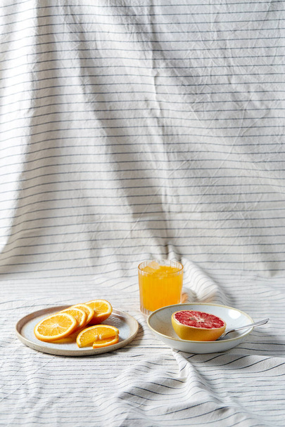 грейпфрут, нарезанный апельсин и стакан сока - Фото, изображение