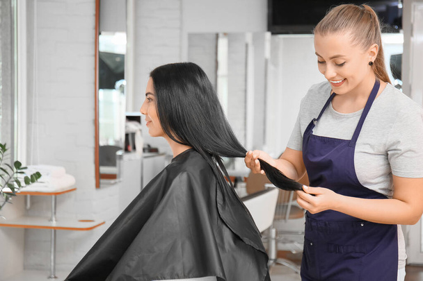 Женщина-парикмахер работает с клиентом в салоне - Фото, изображение