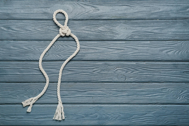 Rope with knot on color wooden background - Photo, Image