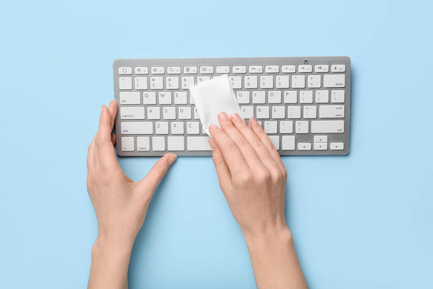 Femme nettoyage clavier d'ordinateur sur fond de couleur - Photo, image