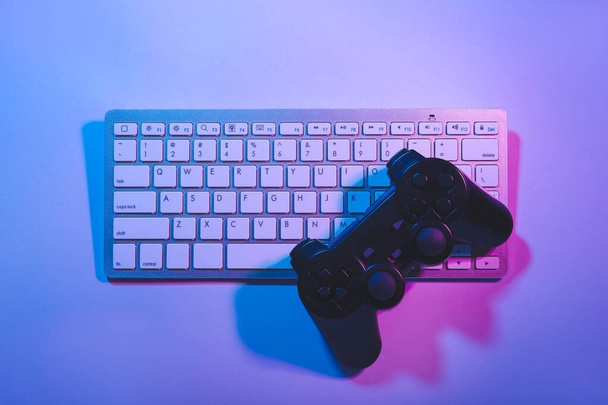 Computertastatur und Gamepad auf farbigem Hintergrund - Foto, Bild