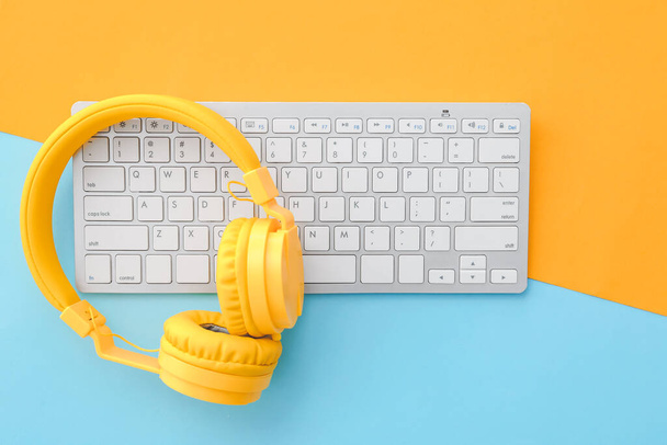 Počítačová klávesnice a sluchátka na barevném pozadí - Fotografie, Obrázek
