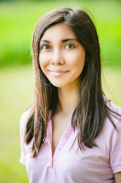Un retrato de una hermosa mujer asiática sonriendo a la cámara. En el contexto de un verde parque de verano. - Foto, imagen