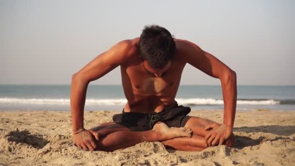 Een jonge man beoefent buiten yoga tegen de achtergrond van de zee - Video