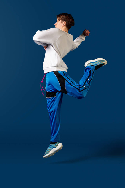 Old-school fashioned young man dancing isolated on blue background - Photo, image