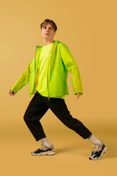 Old-school fashioned young man dancing isolated on yellow background - 写真・画像