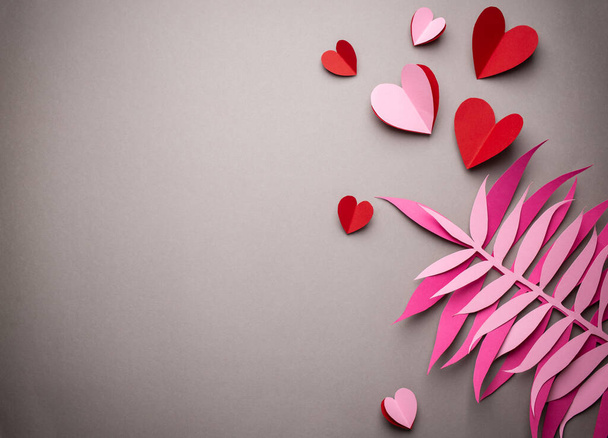 Rode harten gesneden uit papier op roze achtergrond, papier ambachtelijke origami stijl, van boven. Romantische Valentijnsdag achtergrond en liefde concept. Verschillende grootte rode harten bovenaanzicht, papier kunst design - Foto, afbeelding