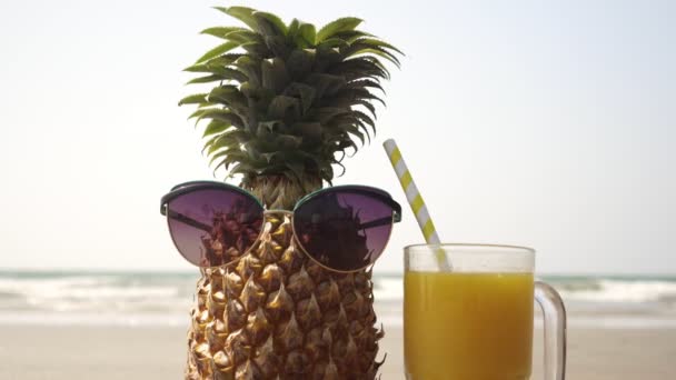 Güneş gözlüklü komik ananas ve denizin arka planında bir bardak meyve suyu. - Video, Çekim