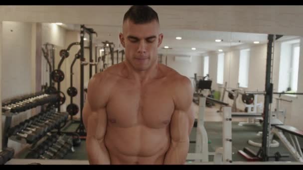 Muskulöser junger Mann trainiert im Fitnessstudio und macht Übungen mit einer w-förmigen Langhantel mit großem Gewicht, die den Bizeps hochpumpt - Filmmaterial, Video