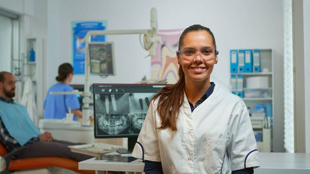 Στοματολόγος γιατρός χαμογελά στην κάμερα στο οδοντιατρείο - Φωτογραφία, εικόνα