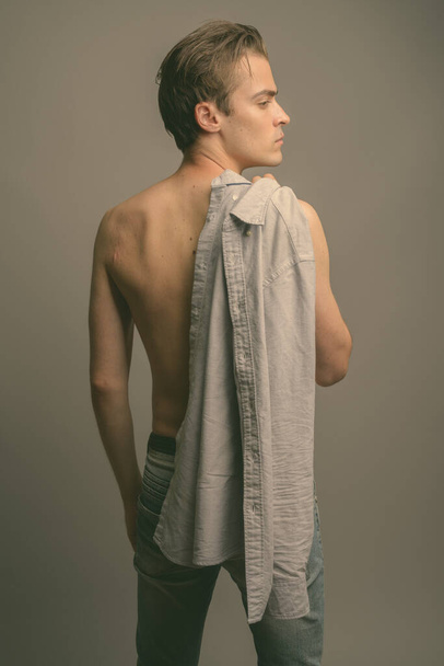 Студийный снимок молодого красивого мужчины без рубашки на сером фоне - Фото, изображение