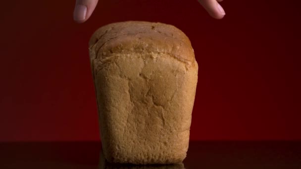 Kırmızı arka planda, yansıtıcı yüzeyde duran çıtır çıtır ekmek dilimlerinin olduğu lezzetli ekmek dilimlerini kapatın. Stok görüntüleri. Erkek el yavaşça bir parça beyaz ekmek alıyor..  - Video, Çekim