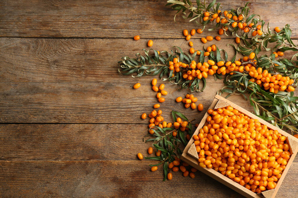 Ripe sea buckthorn berries on wooden table, flat lay. Space for text - Foto, Bild