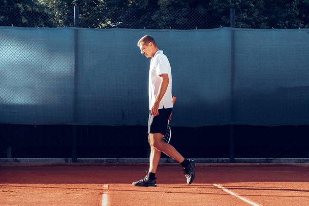 Tennis player standing with racket on tennis court - Fotó, kép