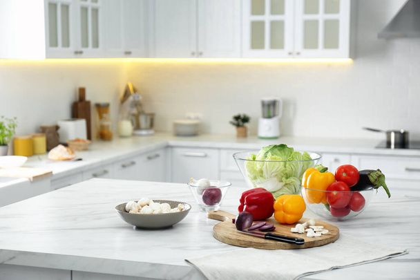 Different fresh vegetables and mushrooms on white table in modern kitchen. Space for text - Photo, image