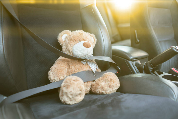 ursinho de pelúcia pequeno protegido com cinto de segurança no carro, segurança de acidente de veículo - Foto, Imagem