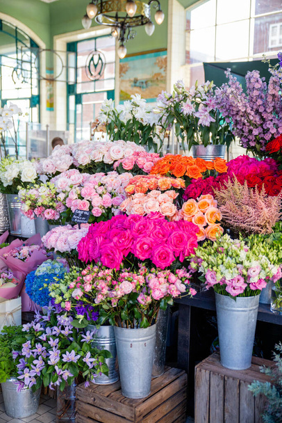 Display of colorful flowers on metal pots inside a shop - Photo, Image
