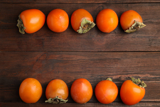 Delicious fresh persimmons on wooden table, flat lay. Space for text - Valokuva, kuva