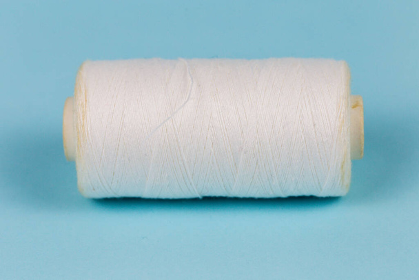 Textile industry, thread and needle, blue background, place for advertising or text - Fotó, kép