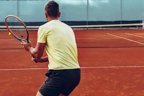Tennis player standing with racket on tennis court - Foto, imagen