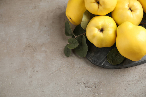 Fresh ripe organic quinces with leaves on grey table, above view. Space for text - Valokuva, kuva